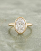    Top-down view of a 2 CT oval cut lab grown diamond engagement ring in a yellow gold bezel setting with milgrain trim.