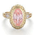 Direct top-down view displaying a 4 CT blush pink oval lab diamond with carved petal halo and pear side stones