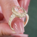 High-angle perspective on hand showing the botanical engraved bezel and center pink oval diamond.