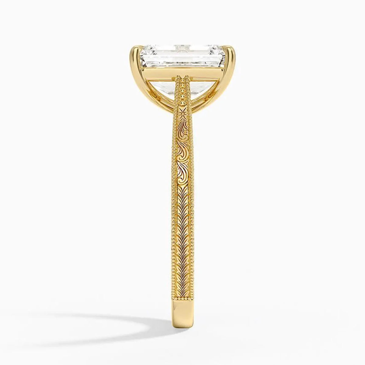 Side profile view of a 3 CT emerald cut lab diamond engagement ring showing hand-engraved scrollwork on a yellow gold band.