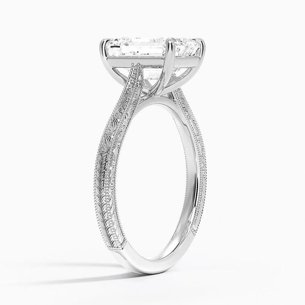 Perspective view of a 3 CT emerald cut lab diamond engagement ring with vintage hand engraving in white gold.