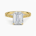 Direct top-down view of a 3 CT emerald cut lab grown diamond engagement ring with vintage carved shoulders in yellow gold.