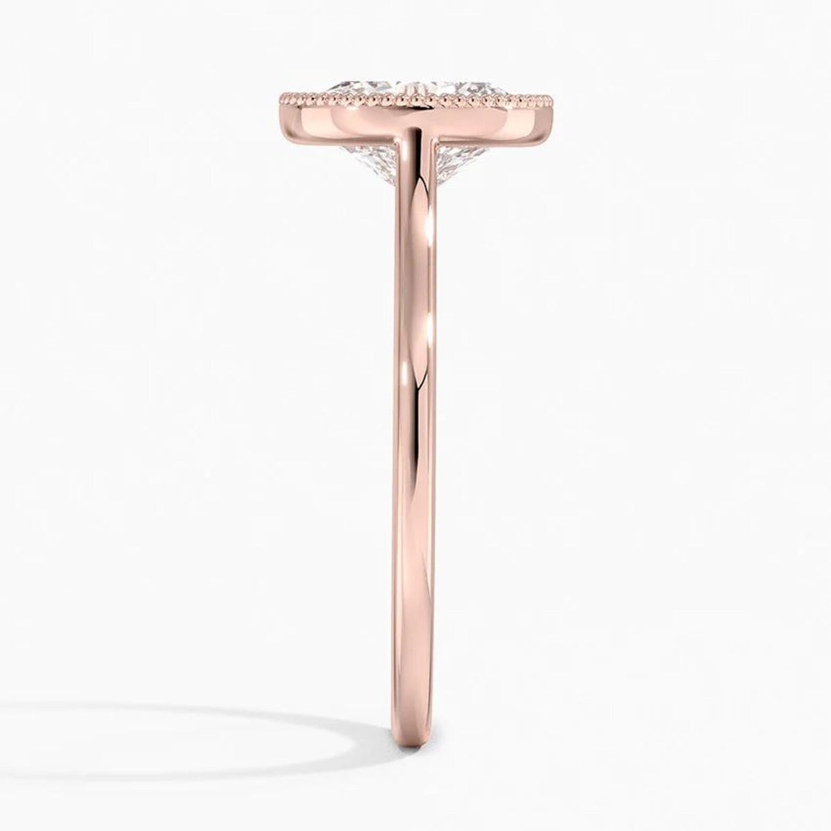 Direct side profile view of a rose gold oval diamond engagement ring with a milgrain bezel edge.