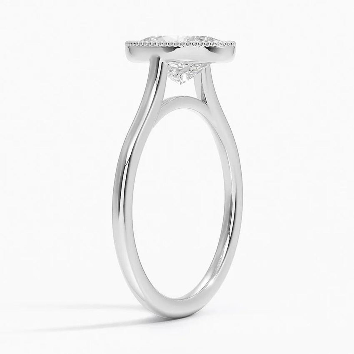 Angled side profile showing smooth white gold band and cathedral support under the milgrain bezel setting.