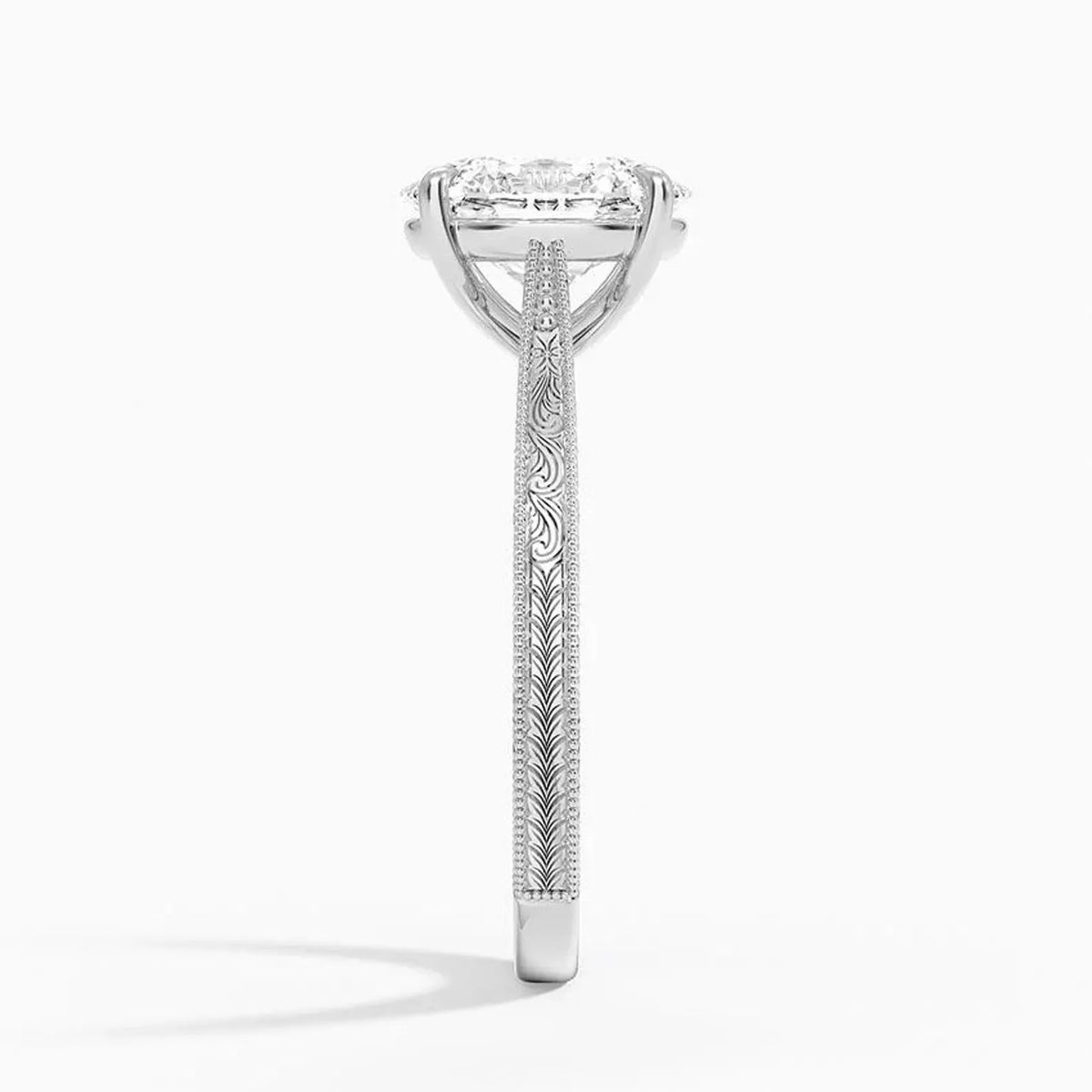Side profile view showing intricate scrollwork engraving and milgrain detailing on a white gold ring band.