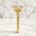 Side profile view of a 3 CT oval lab grown diamond engagement ring featuring intricate scrollwork and milgrain on a yellow gold band.