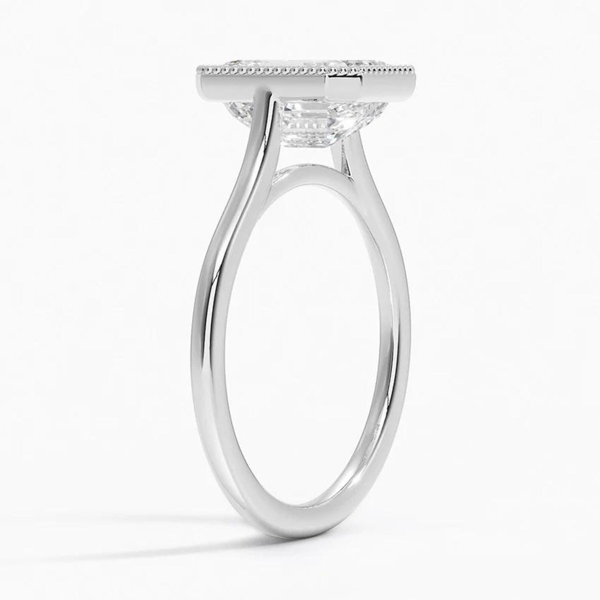 Three-quarter side angle showing the open setting and milgrain bezel edge of a 4 CT emerald lab diamond ring in white gold.