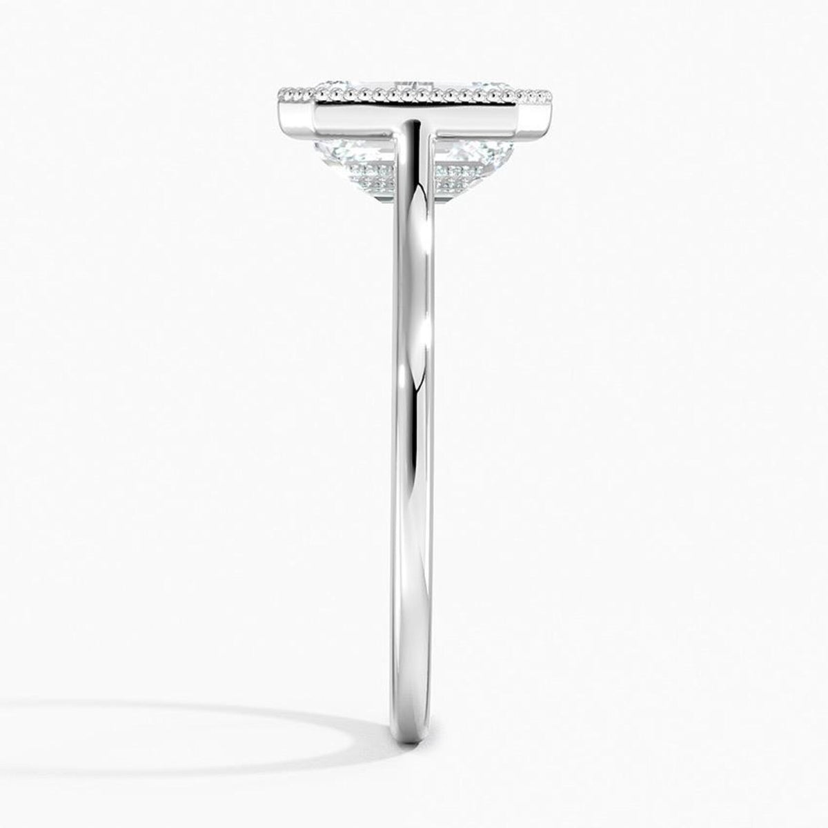 Direct side profile view of a white gold emerald cut lab grown diamond solitaire ring with milgrain detailing.