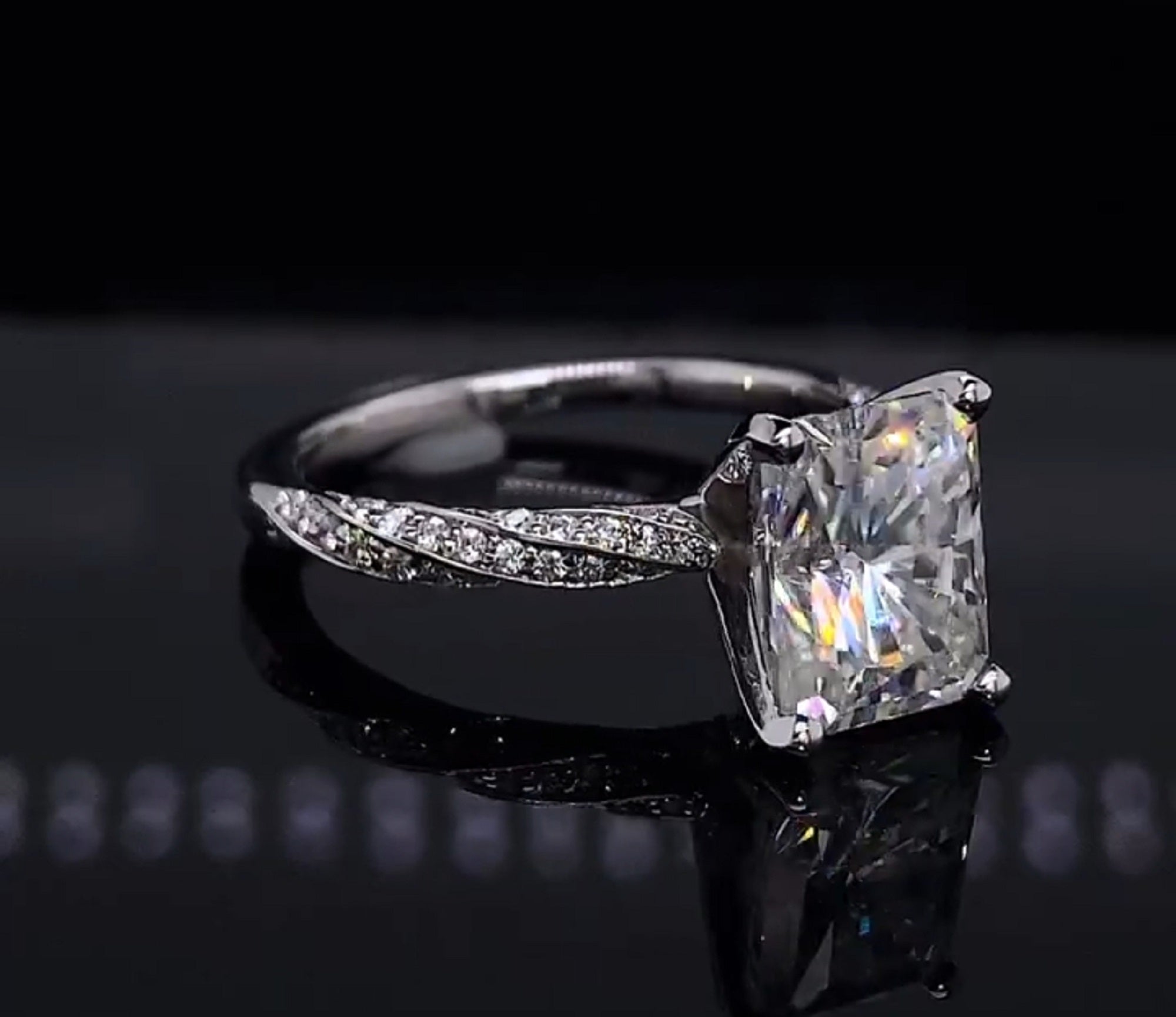 Slightly turned view highlighting the 4-prong setting and delicate twisted pavé shank of the white gold radiant ring.