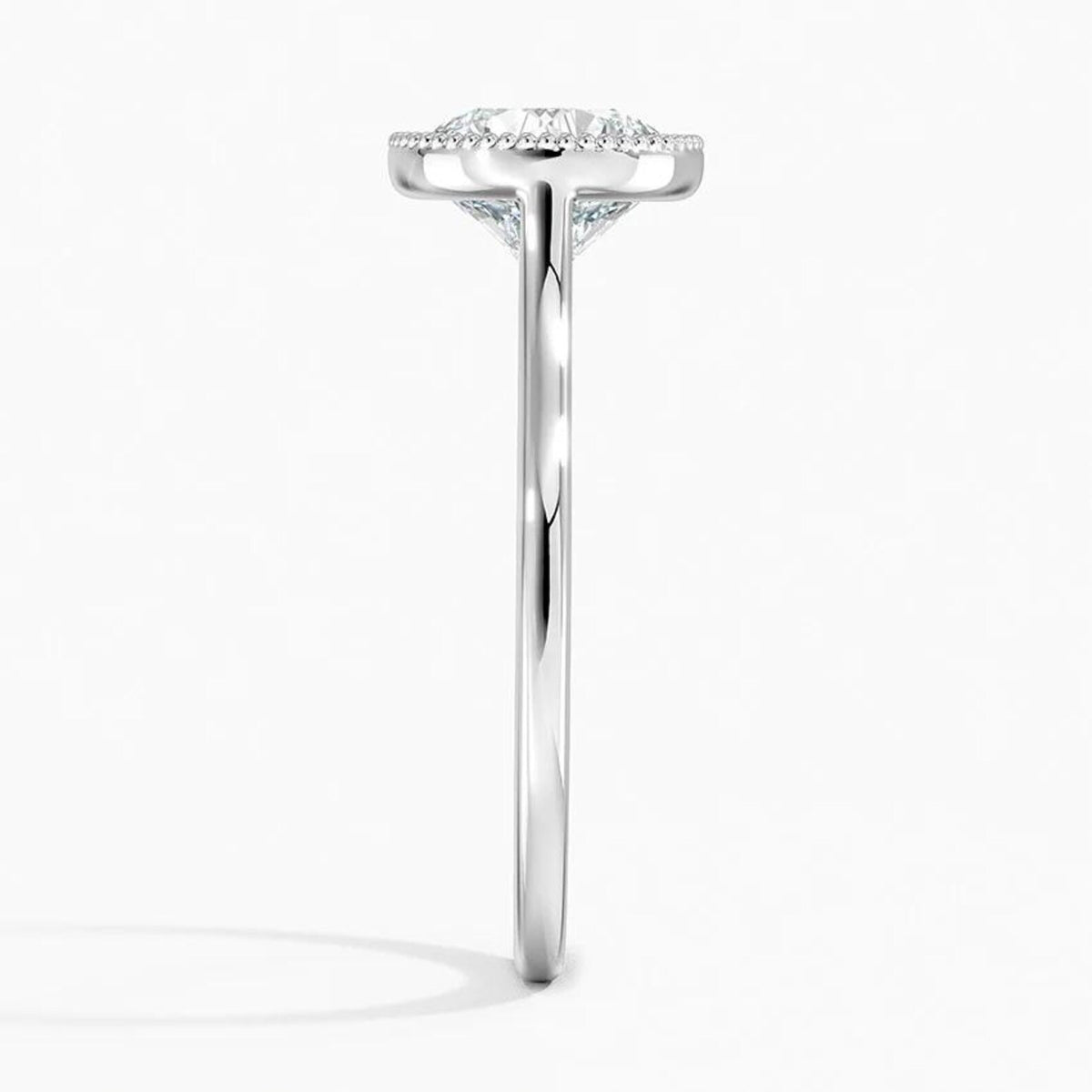 Direct side profile view of a polished white gold ring band with a milgrain bezel setting holding a round lab diamond