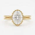 Top-down view of a 3 CT oval cut lab grown diamond engagement ring framed by a scalloped bezel on a yellow gold double band.