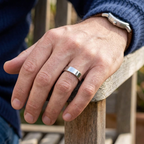 Outdoor lifestyle view showing a men's high-polish flat top wedding ring worn on the hand