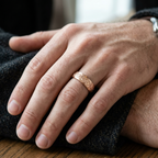 Close-up of a man wearing the rose gold engraved scroll wedding band on his finger.