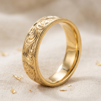 Angled view showing the smooth polished interior and engraved exterior of a yellow gold band