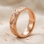Angled studio view of a men's rose gold filigree wedding band with milgrain borders.