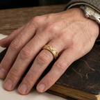 On-hand lifestyle photo of a man wearing a yellow gold vintage engraved scrollwork band.