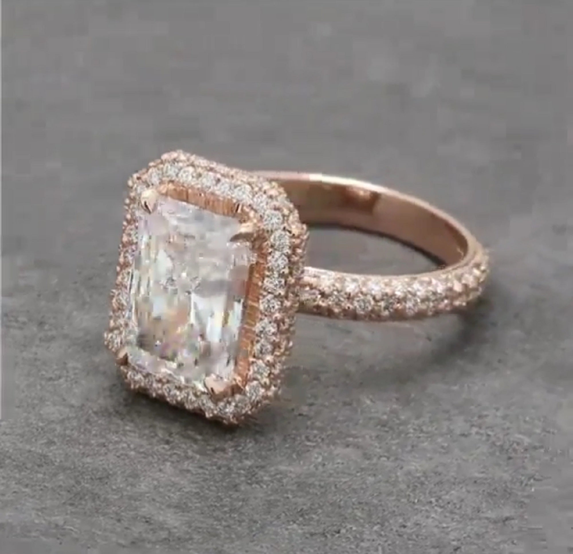 Front angled view showcasing the 4 carat elongated radiant center diamond framed by a micro-pavé diamond halo in rose gold.