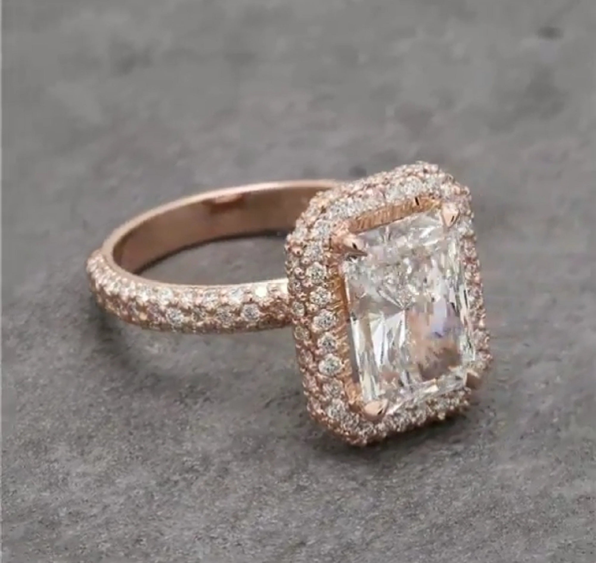 Front-right perspective displaying the full 4 CT radiant lab diamond, rose gold halo border, and pavé shank.