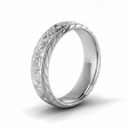 Angled 3/4 view of a men's white gold engraved scrollwork wedding band with leaf chevron edges.