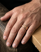 Lifestyle photo of a man's hand wearing a rose gold segmented block brushed wedding band