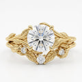 Overhead view showing a 3 ct round brilliant lab diamond in a yellow gold botanical leaf motif ring set with small accent diamonds.
