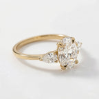 Angled perspective view of a 4 carat oval lab grown diamond engagement ring with pear-shaped side stones set in 14K yellow gold.