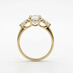 Side profile view of a yellow gold three stone ring showing the basket setting under a 4 ct oval lab grown diamond.