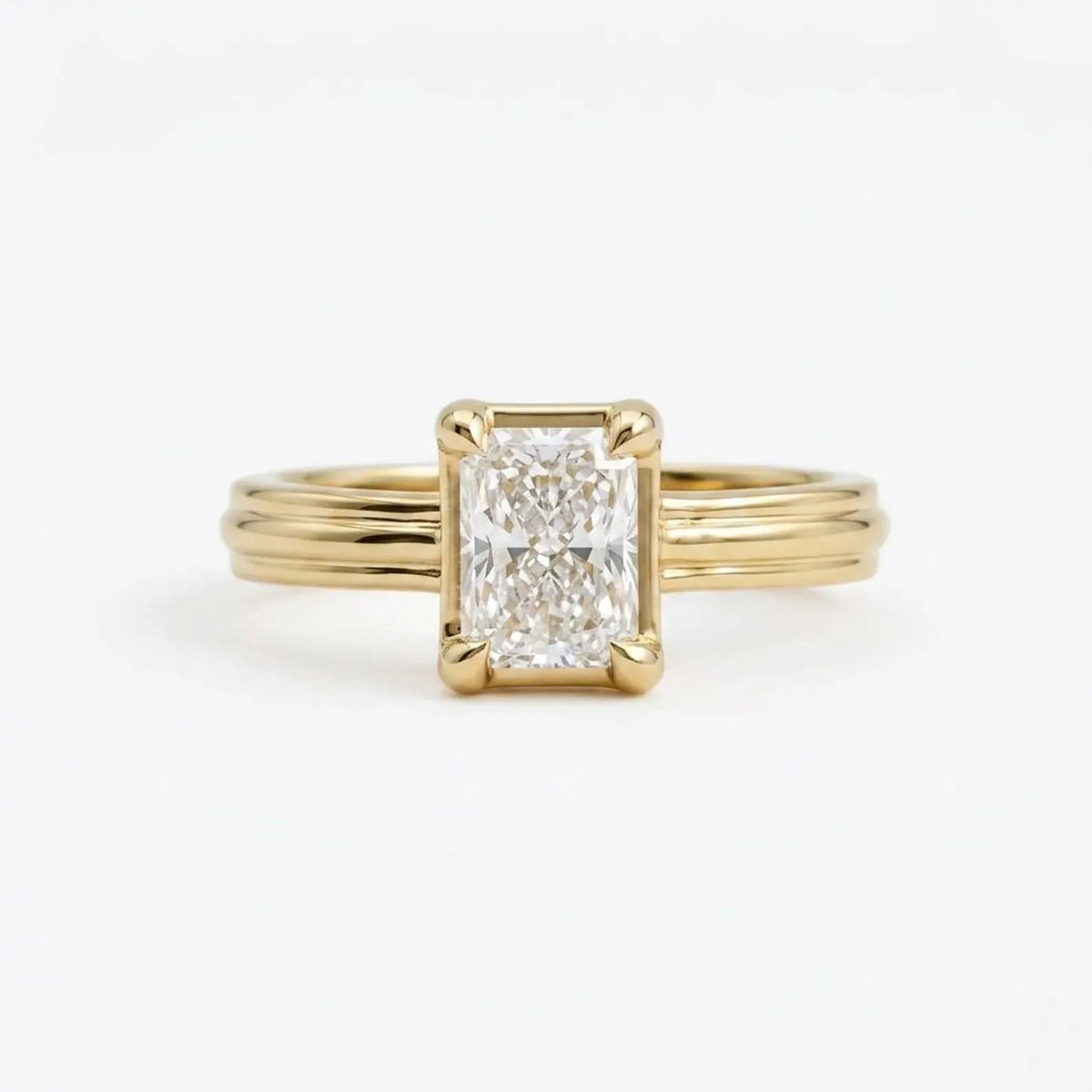 Front face-up view of a 3 carat radiant cut lab grown diamond engagement ring with a 14K yellow gold grooved band.