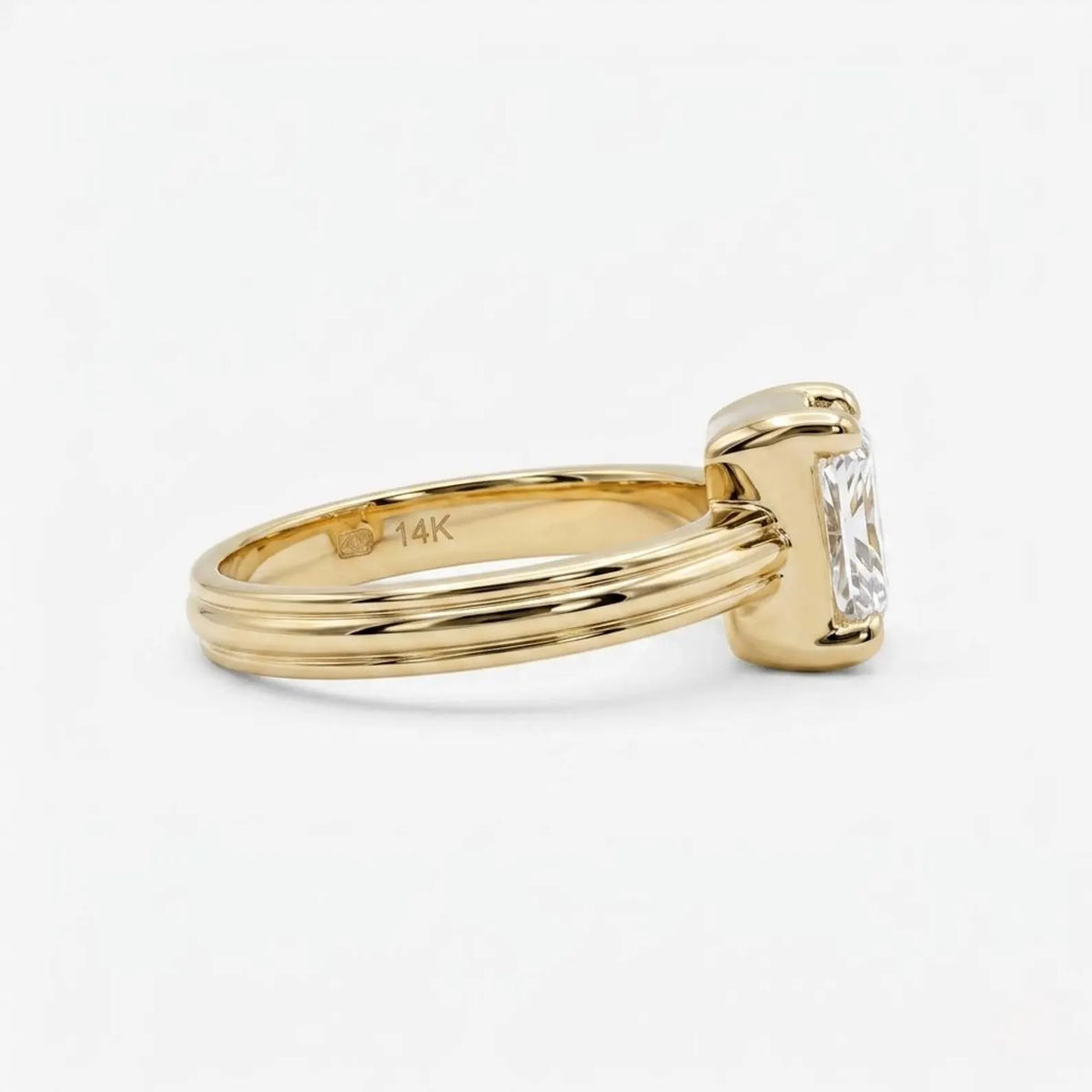 Side perspective of the grooved 14K yellow gold band highlighting the internal 14K gold authenticity stamp and 3ct radiant stone.