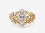 3 CT oval cut lab grown diamond engagement ring set in 14k yellow gold featuring a nature inspired floral leaf motif and matching chevron band.
