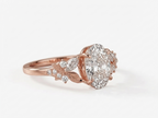 Side profile view of a rose gold oval cut lab grown diamond engagement ring showing carved leaf details and marquise accent diamonds.