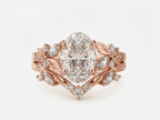 Top front view of a 3 carat oval lab diamond engagement ring set with floral leaf side clusters in 14k rose gold.