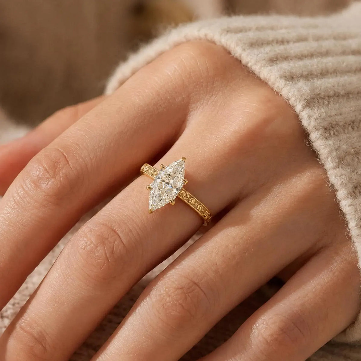 On-hand view of a 3 CT marquise cut lab grown diamond solitaire engagement ring with a yellow gold floral carved band.