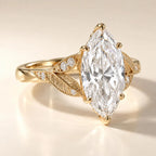 Angled view of a 4 CT marquise cut lab grown diamond engagement ring featuring leaf engraved split shoulders in yellow gold.