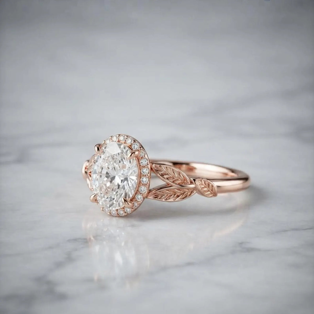 Side profile angle of a rose gold 2 CT oval lab diamond halo ring featuring leaf engraved split shoulders on marble.