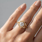 On-hand view in natural light of a 3 CT round cut lab grown diamond ring with botanical leaf shoulders.