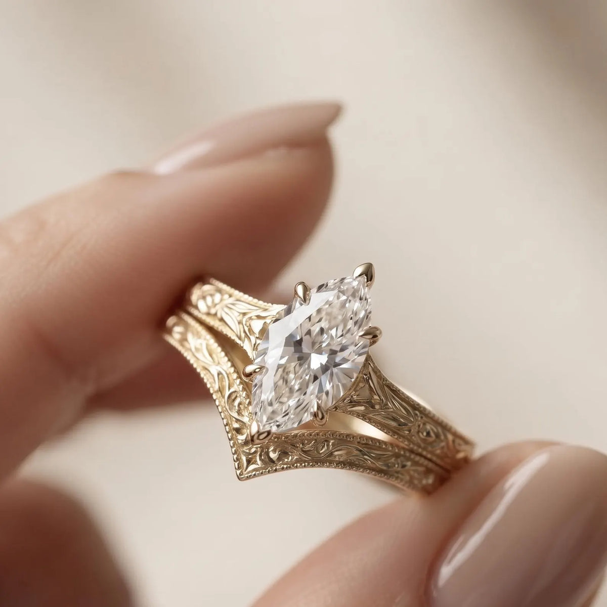 Hand holding a 2 carat marquise cut lab grown diamond ring with matching hand-carved yellow gold chevron wedding band.