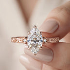 Close-up of hand holding a 3 CT marquise lab diamond engagement ring with detailed milgrain scrollwork.