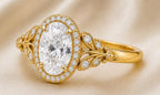 Macro view of a 3 CT oval lab grown diamond halo ring in yellow gold with sculpted leaf filigree shoulders.