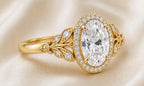 Side perspective view of a yellow gold 3 CT oval lab diamond ring featuring pave leaf accents and milgrain halo.
