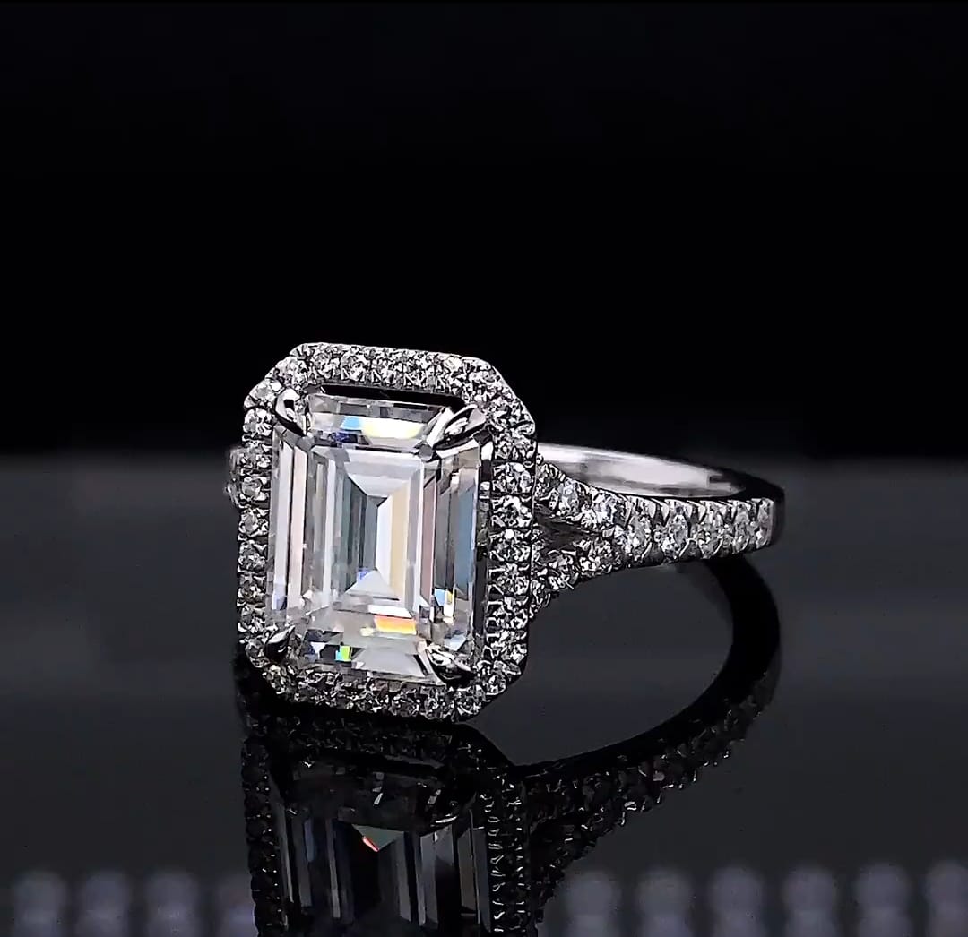Top-down view of a 3 CT emerald cut lab grown diamond halo engagement ring with a split shank band.