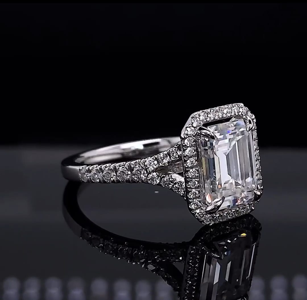 Angled profile view of an emerald cut lab grown diamond ring highlighting the sparkling diamond halo and prong setting.
