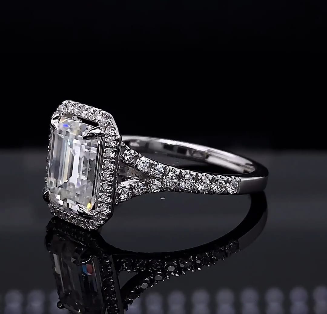 Close-up angled view of a 3 CT emerald cut lab grown diamond ring resting on a reflective black surface.