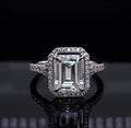 Direct front view of a stunning 3 CT emerald cut lab grown diamond halo engagement ring in white metal.