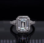 Direct front view of a stunning 3 CT emerald cut lab grown diamond halo engagement ring in white metal.