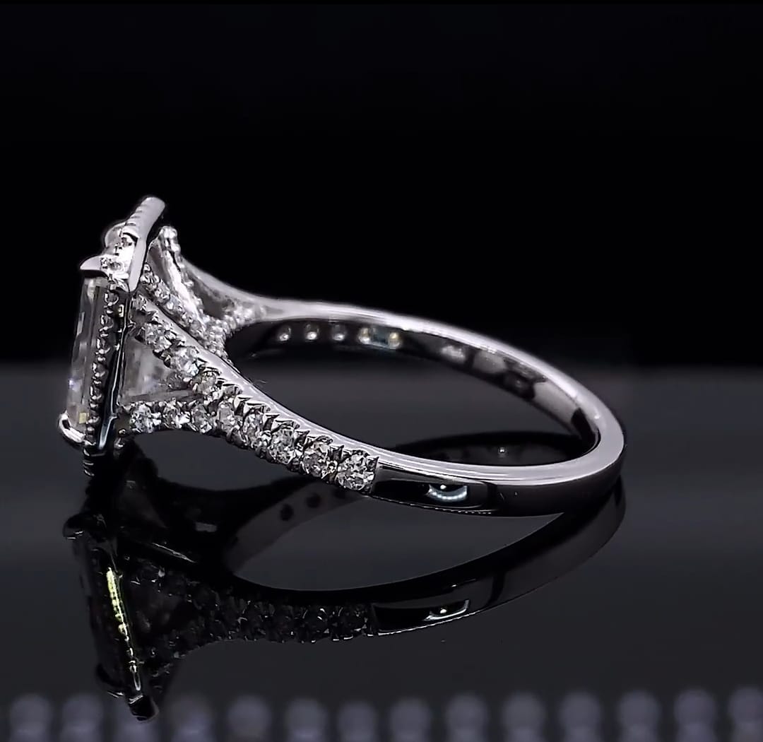 Low angle side view detailing the gallery, prong setting, and pavé diamond split shank of an emerald cut ring.
