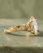Side angle of a 4 carat marquise lab diamond engagement ring featuring cathedral filigree shoulders and engraved scrollwork.