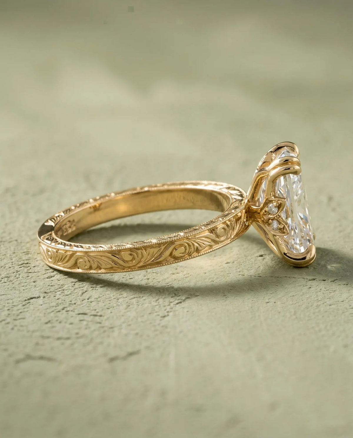 Side profile view of a 3 CT elongated cushion lab grown diamond ring with hand-engraved yellow gold band and floral basket gallery.