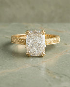 Top-down view of a 3 CT elongated cushion cut lab diamond set in a vintage hand-engraved yellow gold ring with double prongs.