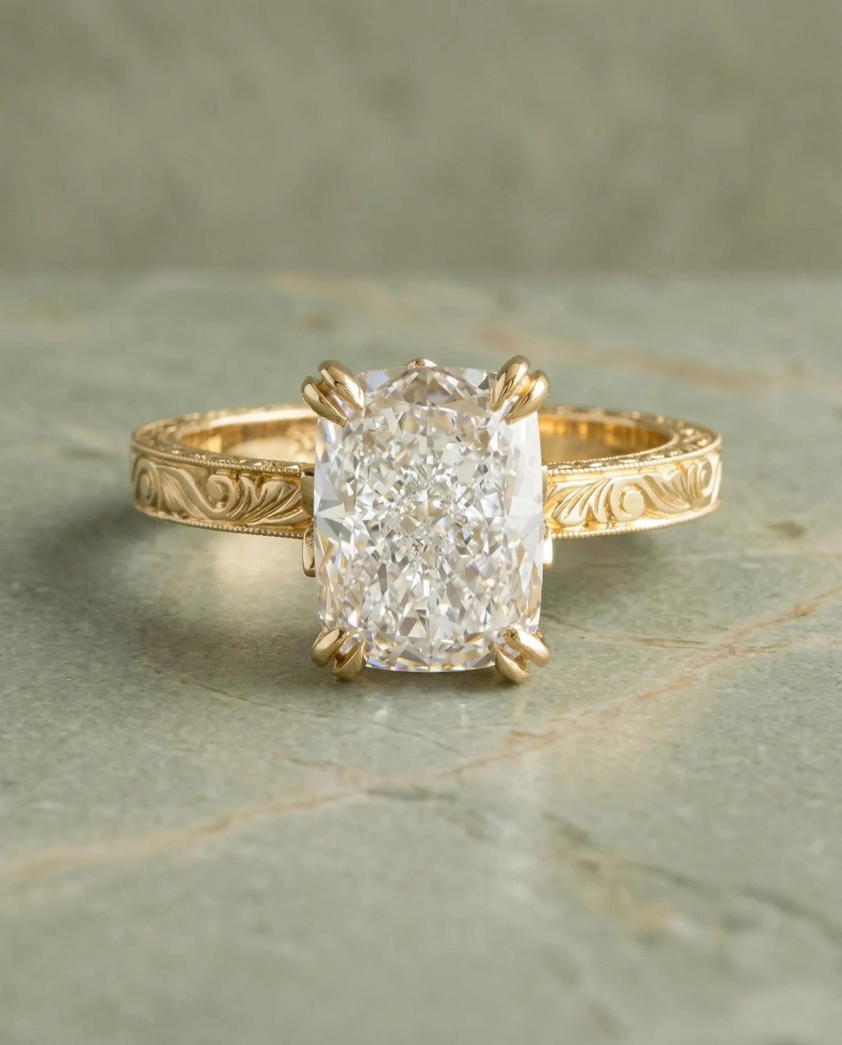 Top-down view of a 3 CT elongated cushion cut lab diamond set in a vintage hand-engraved yellow gold ring with double prongs.
